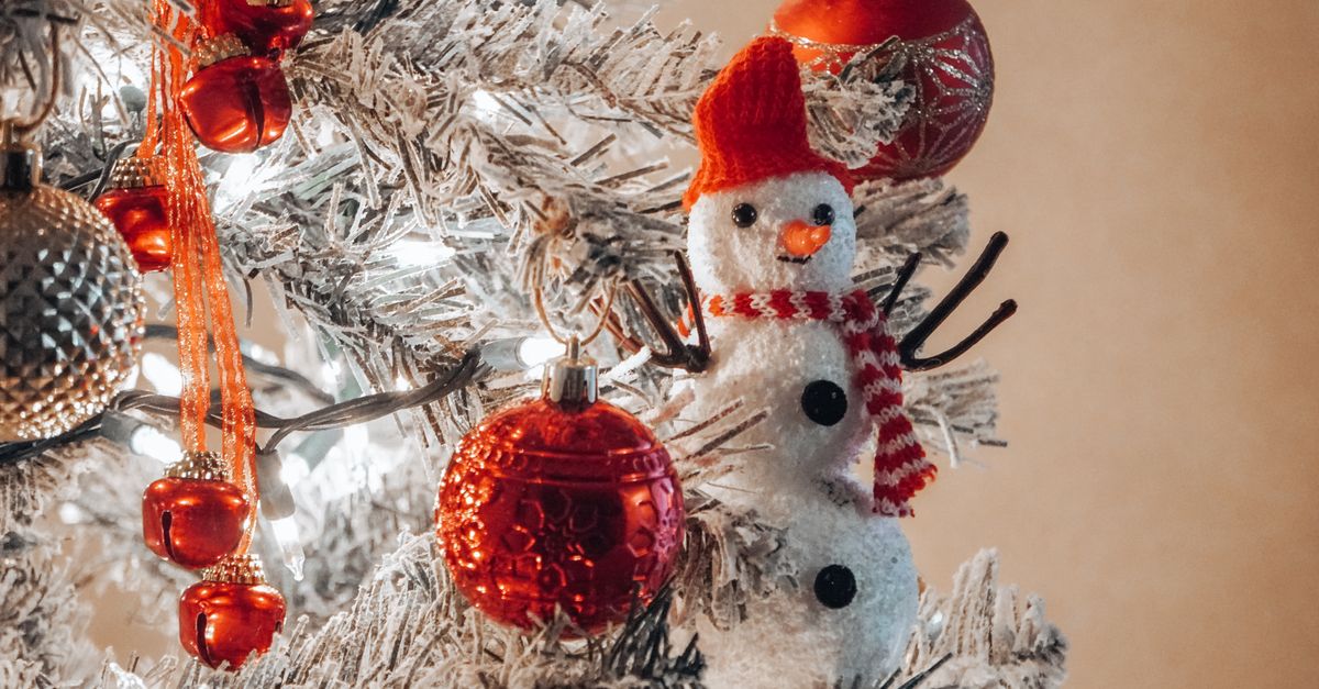 A close-up of a Christmas tree with red ornaments and a snowman decoration, evoking holiday cheer.